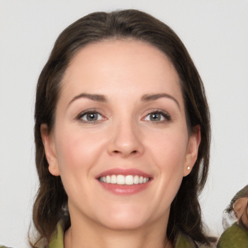 Joyful white young-adult female with medium  brown hair and grey eyes