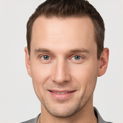 Joyful white young-adult male with short  brown hair and grey eyes