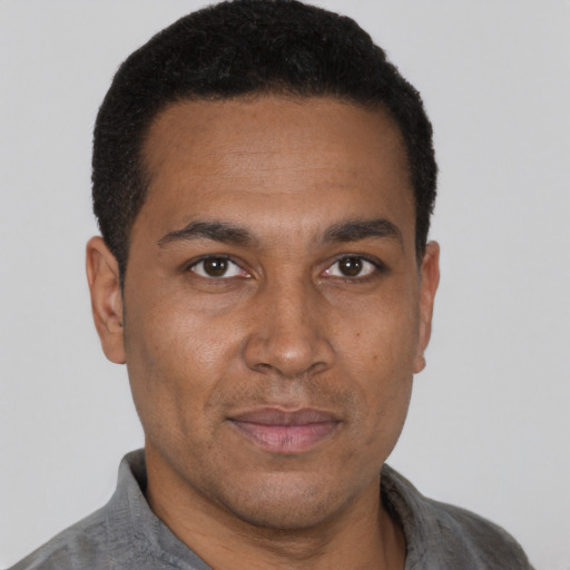 Joyful black adult male with short  black hair and brown eyes