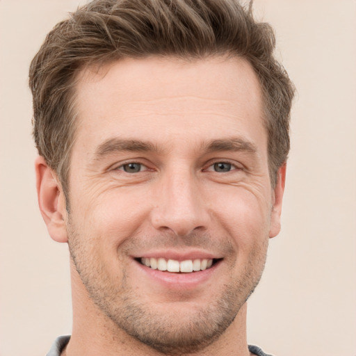 Joyful white young-adult male with short  brown hair and grey eyes