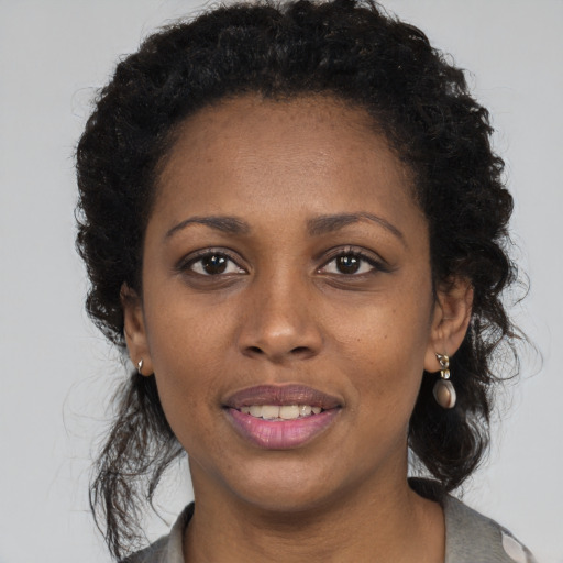 Joyful black young-adult female with long  brown hair and brown eyes
