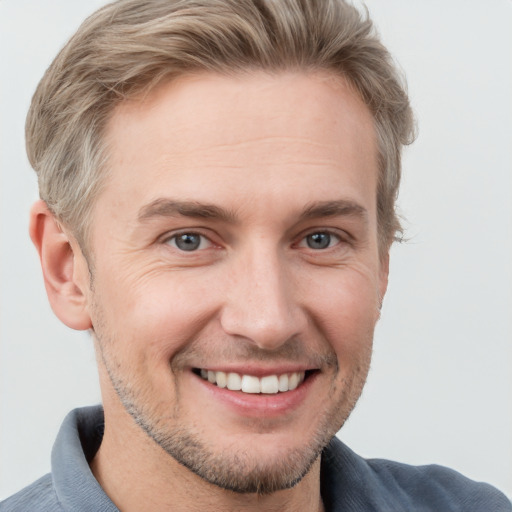 Joyful white adult male with short  brown hair and blue eyes