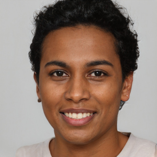 Joyful black young-adult female with short  black hair and brown eyes