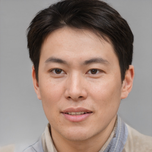 Joyful asian young-adult male with short  brown hair and brown eyes