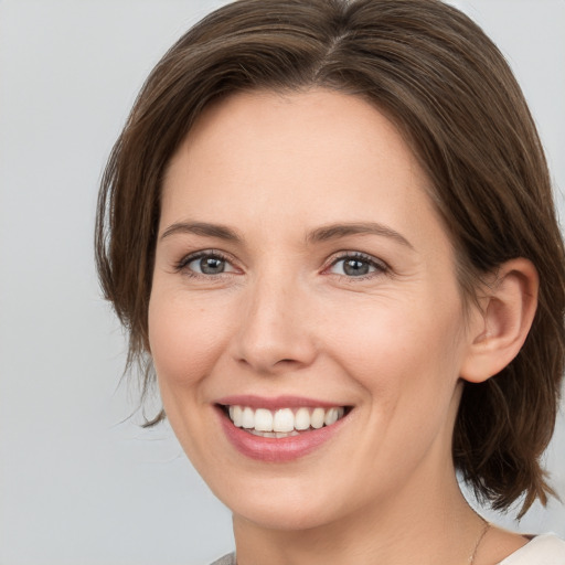 Joyful white young-adult female with medium  brown hair and grey eyes