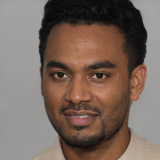 Joyful black young-adult male with short  black hair and brown eyes