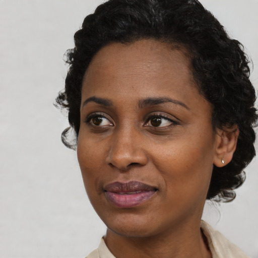 Joyful black young-adult female with short  black hair and brown eyes