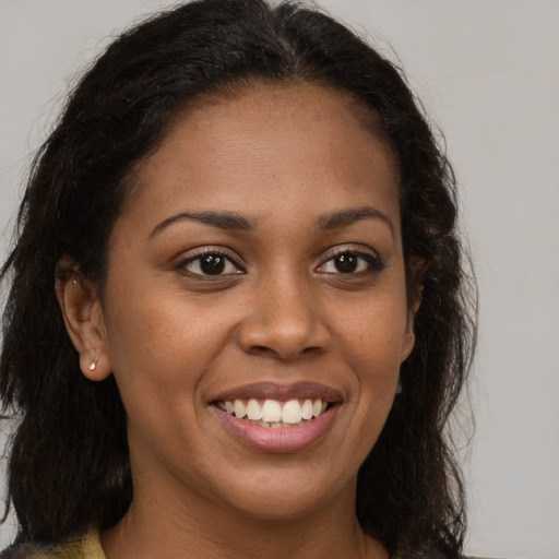 Joyful black young-adult female with long  brown hair and brown eyes