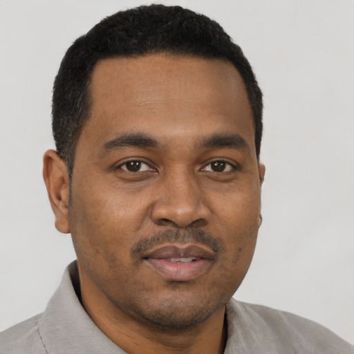 Joyful black young-adult male with short  black hair and brown eyes