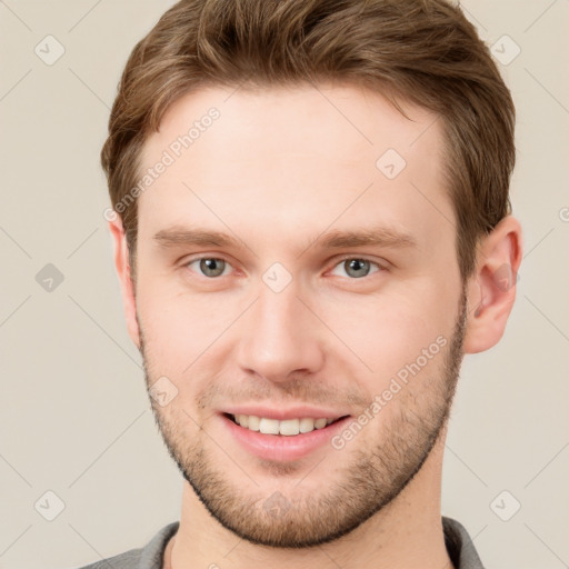 Joyful white young-adult male with short  brown hair and grey eyes