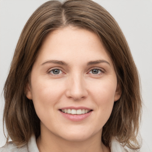 Joyful white young-adult female with medium  brown hair and grey eyes