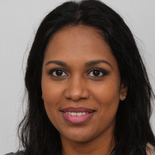 Joyful black young-adult female with long  brown hair and brown eyes