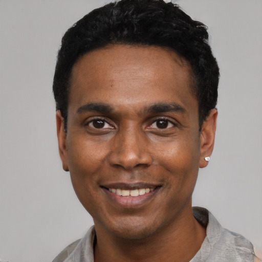 Joyful black young-adult male with short  black hair and brown eyes