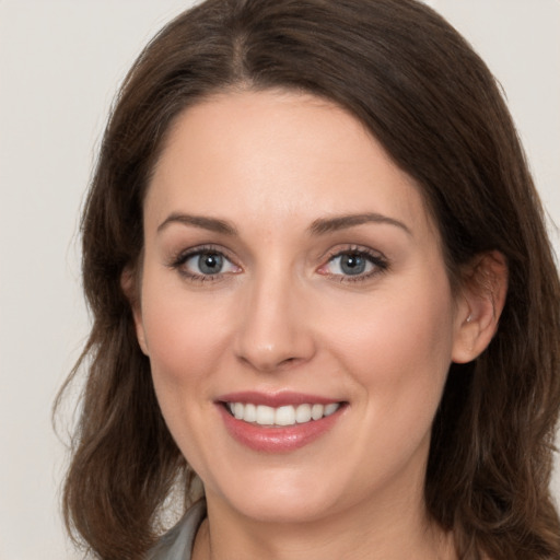 Joyful white young-adult female with medium  brown hair and grey eyes