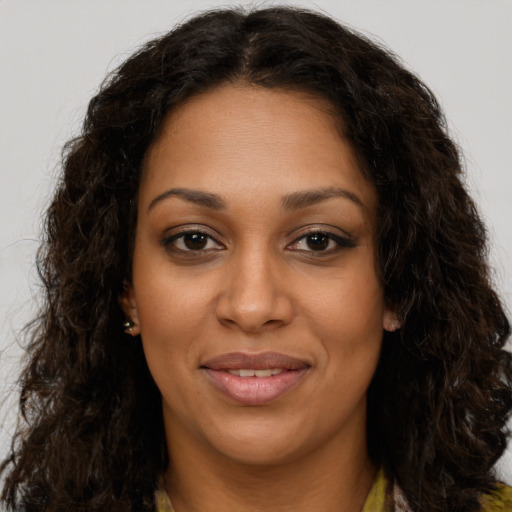 Joyful black young-adult female with long  brown hair and brown eyes