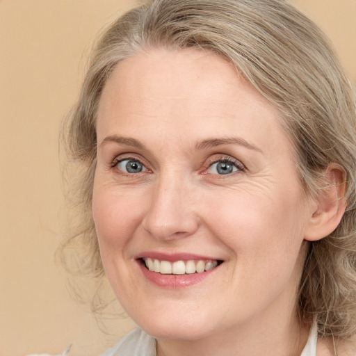 Joyful white adult female with medium  brown hair and blue eyes