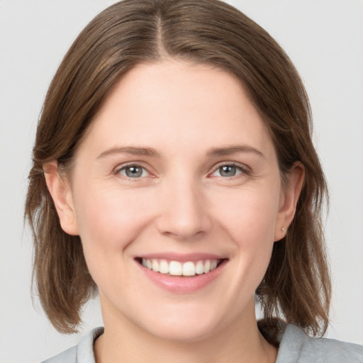 Joyful white young-adult female with medium  brown hair and grey eyes