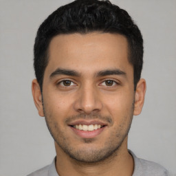 Joyful latino young-adult male with short  black hair and brown eyes