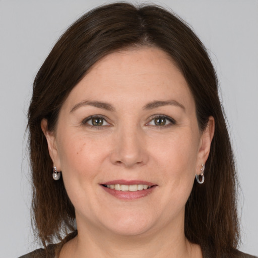 Joyful white adult female with long  brown hair and grey eyes