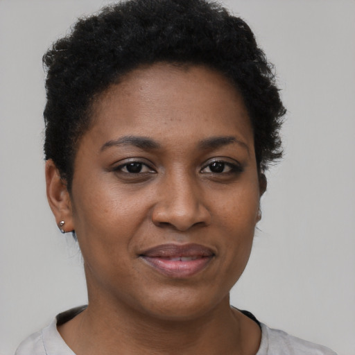 Joyful black young-adult female with short  black hair and brown eyes