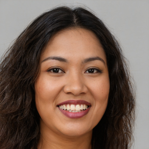 Joyful latino young-adult female with long  brown hair and brown eyes
