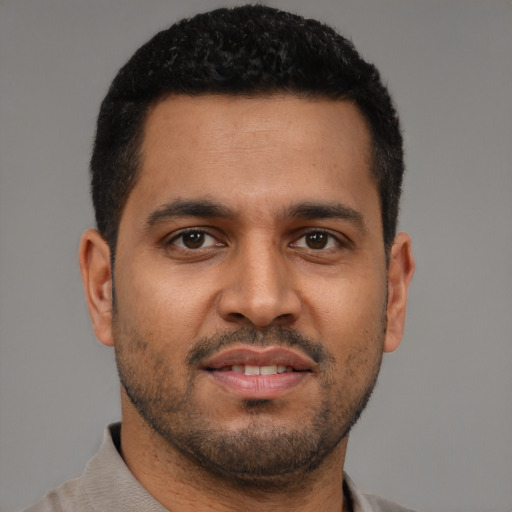 Joyful latino young-adult male with short  black hair and brown eyes