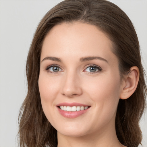 Joyful white young-adult female with long  brown hair and grey eyes