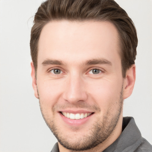 Joyful white young-adult male with short  brown hair and grey eyes