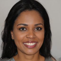 Joyful black young-adult female with long  brown hair and brown eyes