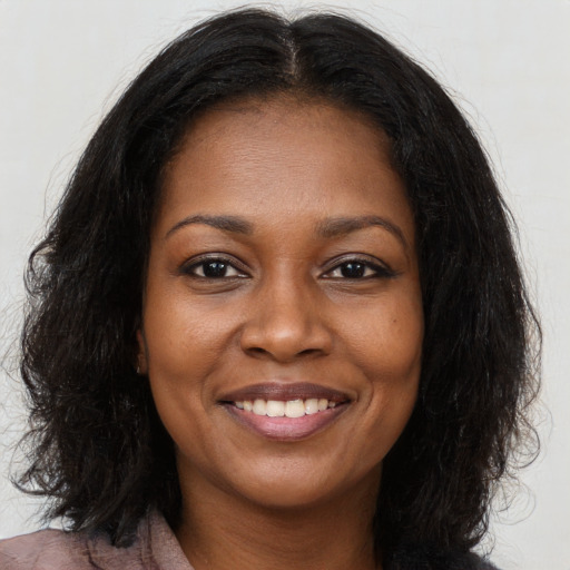 Joyful black young-adult female with long  brown hair and brown eyes