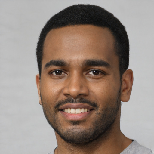 Joyful black young-adult male with short  black hair and brown eyes