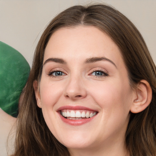 Joyful white young-adult female with long  brown hair and grey eyes