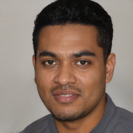Joyful black young-adult male with short  black hair and brown eyes