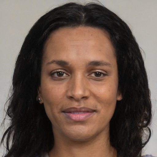 Joyful black adult female with long  brown hair and brown eyes