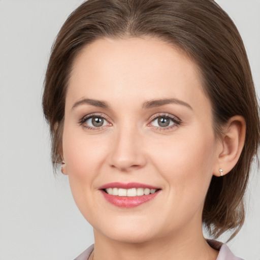 Joyful white young-adult female with medium  brown hair and grey eyes