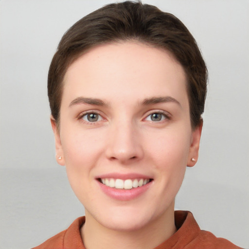 Joyful white young-adult female with short  brown hair and grey eyes