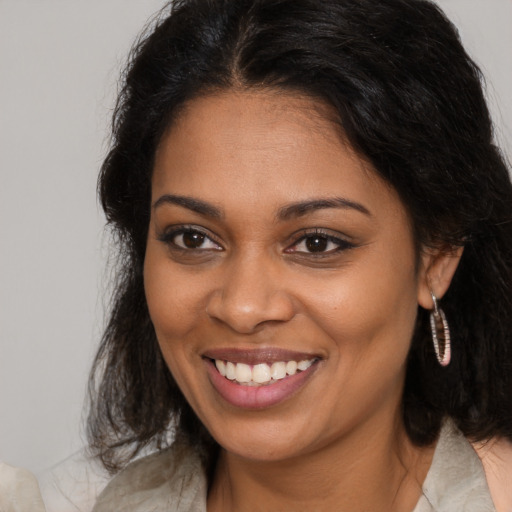 Joyful black young-adult female with long  brown hair and brown eyes