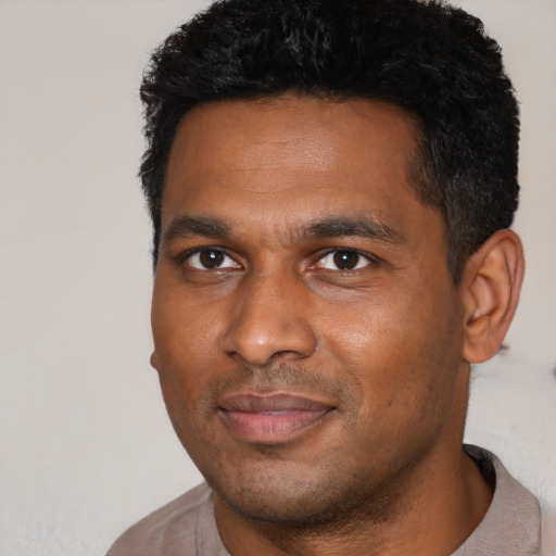 Joyful black young-adult male with short  black hair and brown eyes