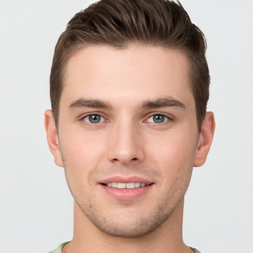 Joyful white young-adult male with short  brown hair and grey eyes