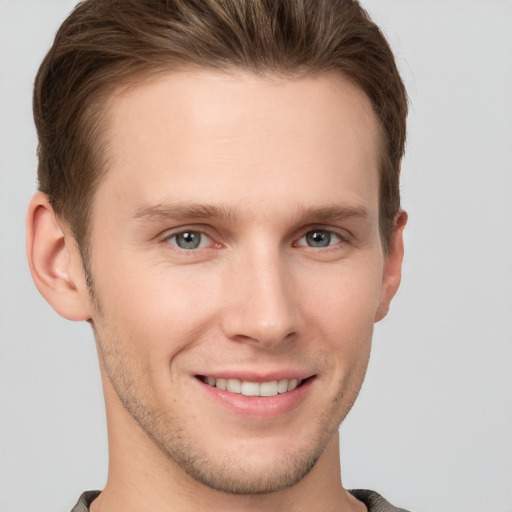 Joyful white young-adult male with short  brown hair and grey eyes