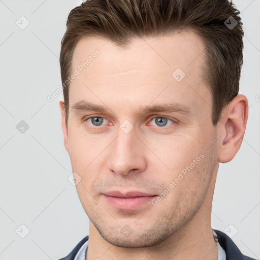 Joyful white young-adult male with short  brown hair and grey eyes