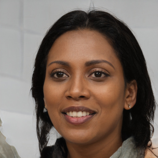 Joyful black young-adult female with long  black hair and brown eyes