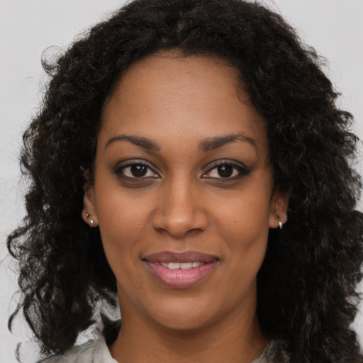 Joyful black young-adult female with long  brown hair and brown eyes
