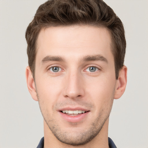 Joyful white young-adult male with short  brown hair and grey eyes