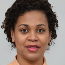 Joyful black adult female with medium  brown hair and brown eyes