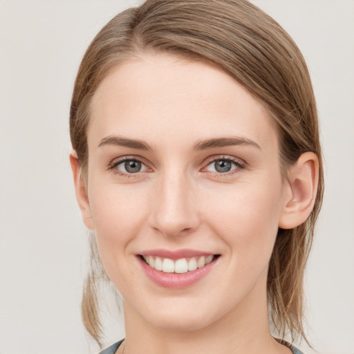 Joyful white young-adult female with medium  brown hair and grey eyes