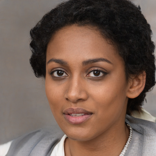Joyful black young-adult female with short  black hair and brown eyes