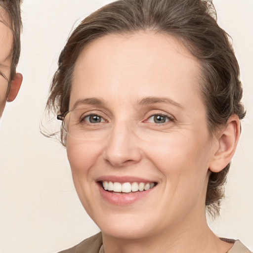 Joyful white young-adult female with medium  brown hair and grey eyes