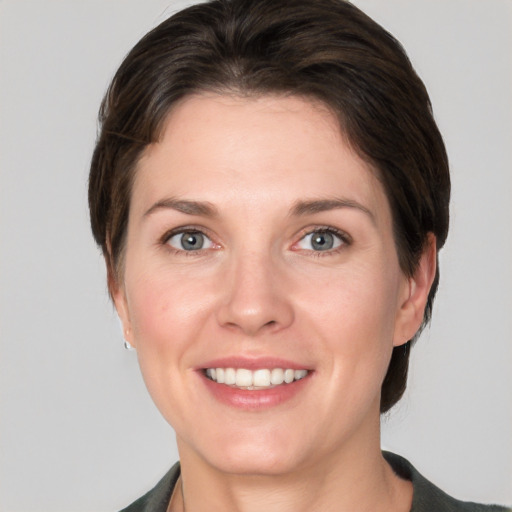 Joyful white young-adult female with short  brown hair and grey eyes