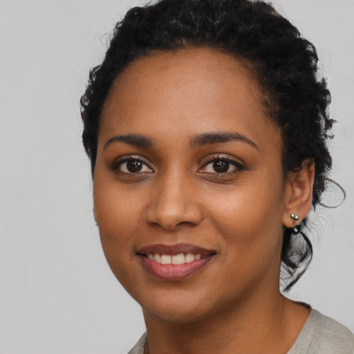 Joyful black young-adult female with long  black hair and brown eyes